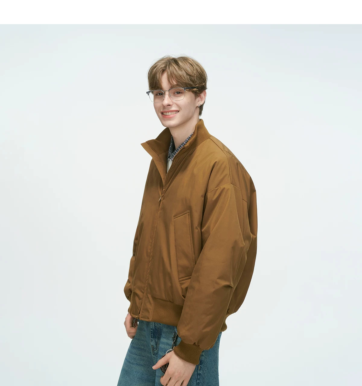 Tan brown bomber jacket three-quarter side view with front patch pockets and ribbed cuffs, solid tan brown fabric finish on relaxed silhouette