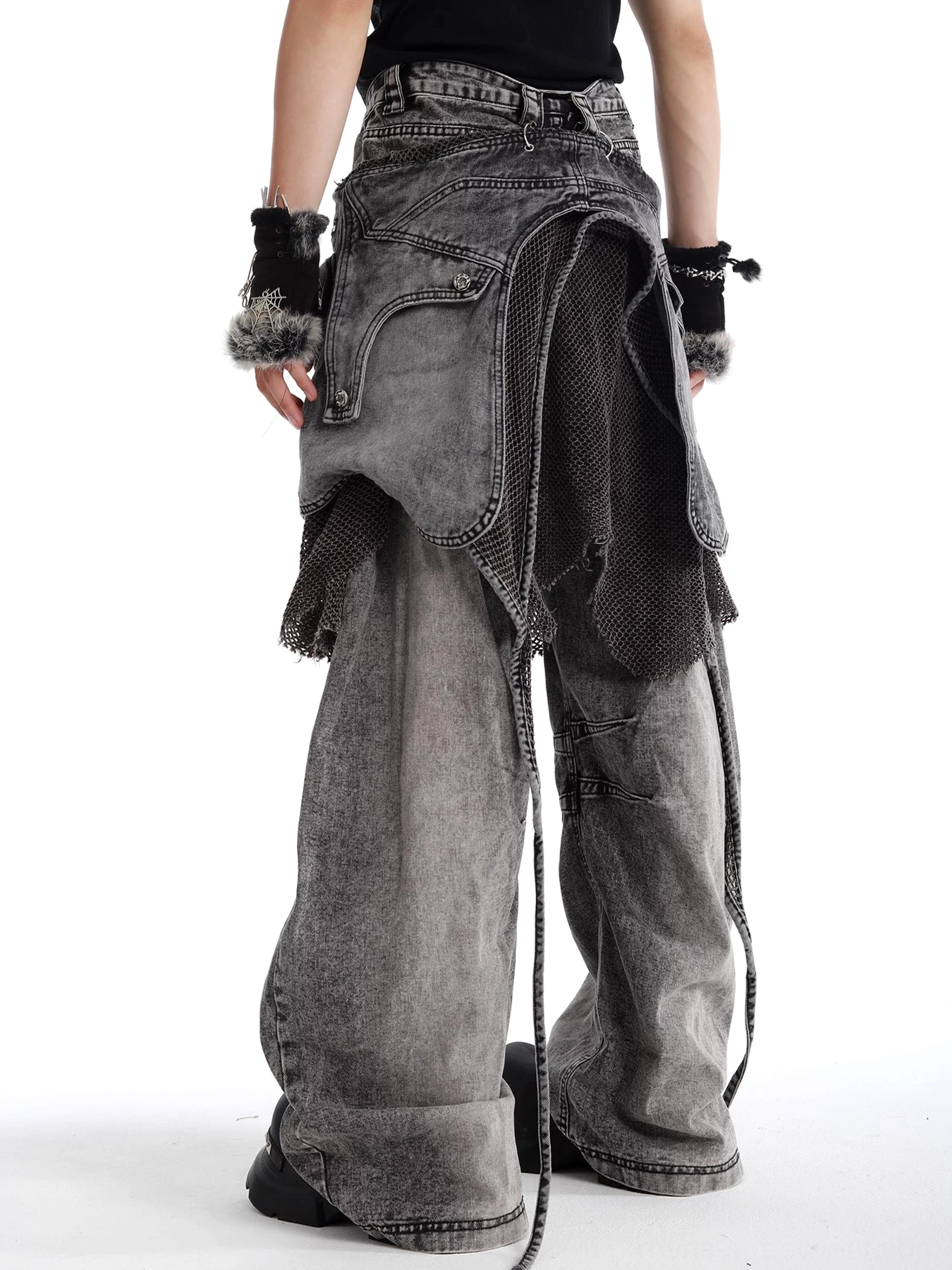 Back three-quarter view of charcoal ash mesh layered baggy jeans with washed grey denim, rear layered pocket panels, drawstrings, and distressed details