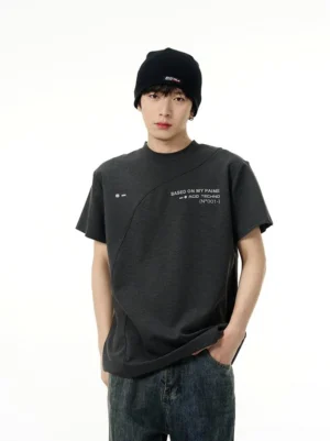 Dark grey Acid Techno graphic tee styled with dark wash jeans and black beanie, showing diagonal seam detail and chest slogan print