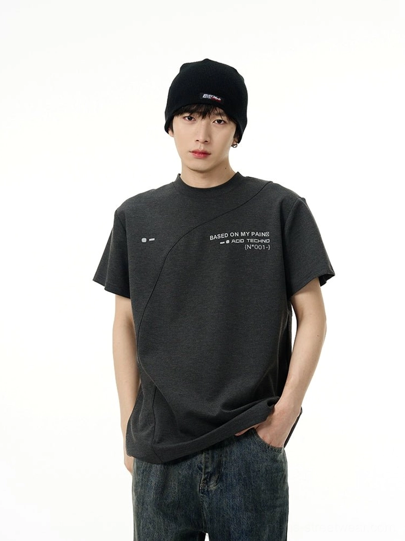 Dark grey Acid Techno graphic tee styled with dark wash jeans and black beanie, showing diagonal seam detail and chest slogan print