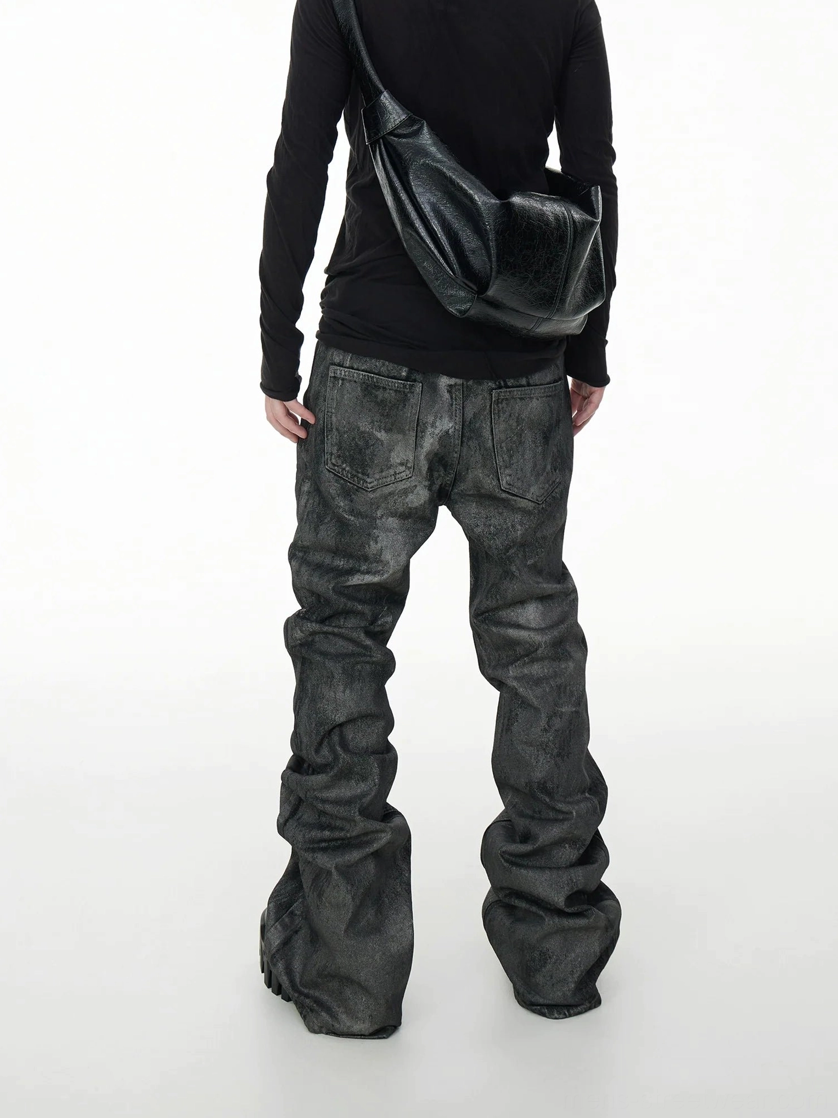 Back view of acid wash coated stacked jeans highlighting rear pocket stitching, oversized flared legs, and mottled vintage denim texture