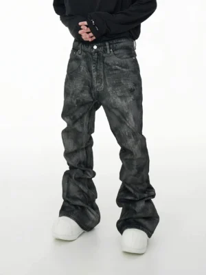 Front view of gray acid wash coated stacked jeans with ultra-wide extra-long streetwear legs styled with a black top and chunky white sneakers