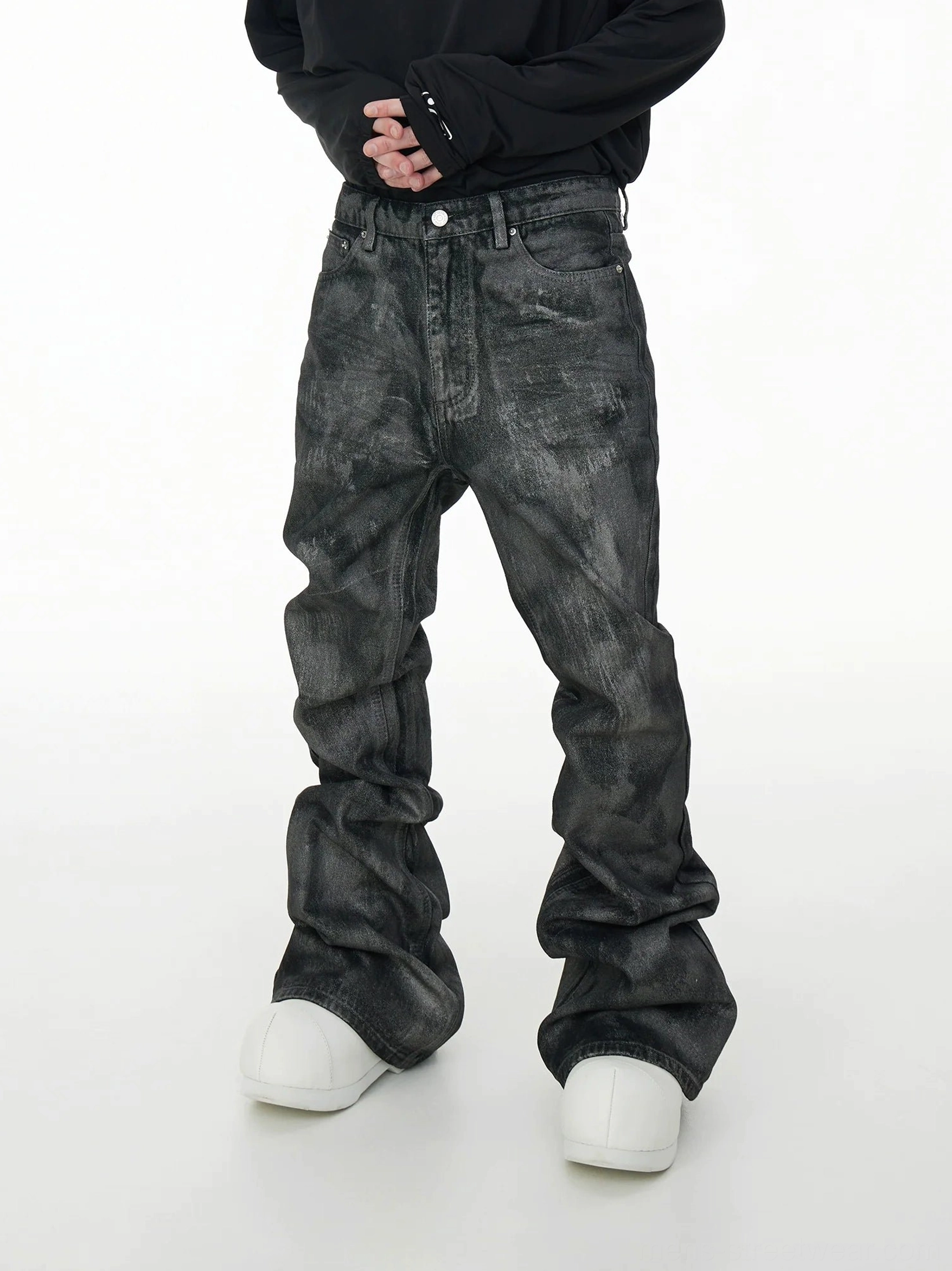 Front view of gray acid wash coated stacked jeans with ultra-wide extra-long streetwear legs styled with a black top and chunky white sneakers