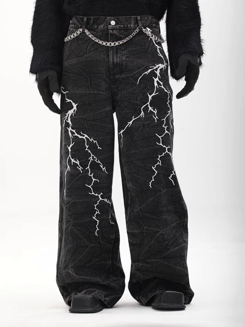 Front three-quarter view of acid-washed black lightning print wide-leg jeans with silver belt chain and cyber-goth styling