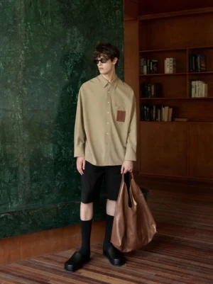 Khaki wool blend oversized streetwear shirt styled with black shorts, socks, loafers, and a brown tote bag