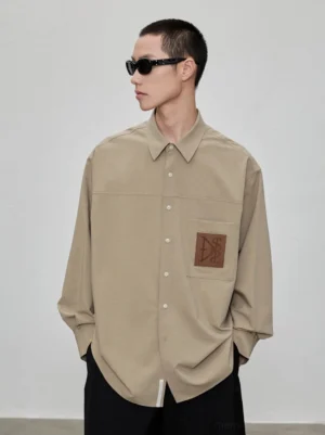Khaki oversized Acubi streetwear shirt with chest patch pocket, genuine leather detail, dropped shoulders, and relaxed long sleeve silhouette