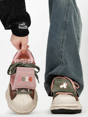 Front view of pink green and brown patchwork shell-toe streetwear sneakers with embroidered 2026 tongue detail and chunky cream sole