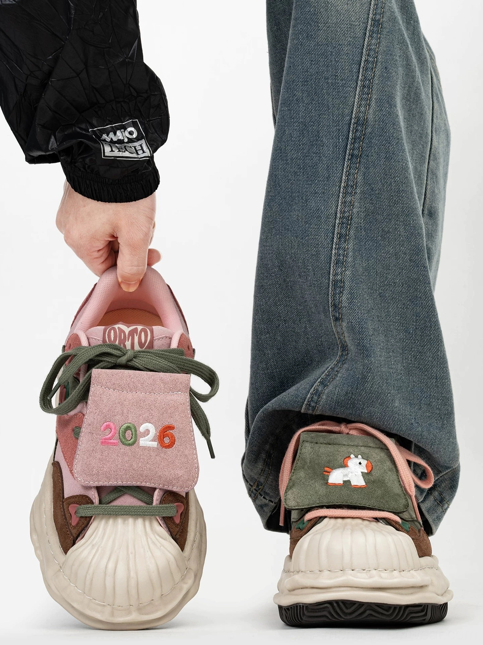 Front view of pink green and brown patchwork shell-toe streetwear sneakers with embroidered 2026 tongue detail and chunky cream sole