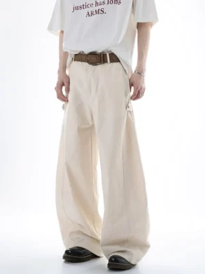 Beige Acubi ultra wide-leg cargo pants shown on a male model in a front full-body studio view with a high waist, brown leather belt styling, draped wide legs, and side cargo pocket