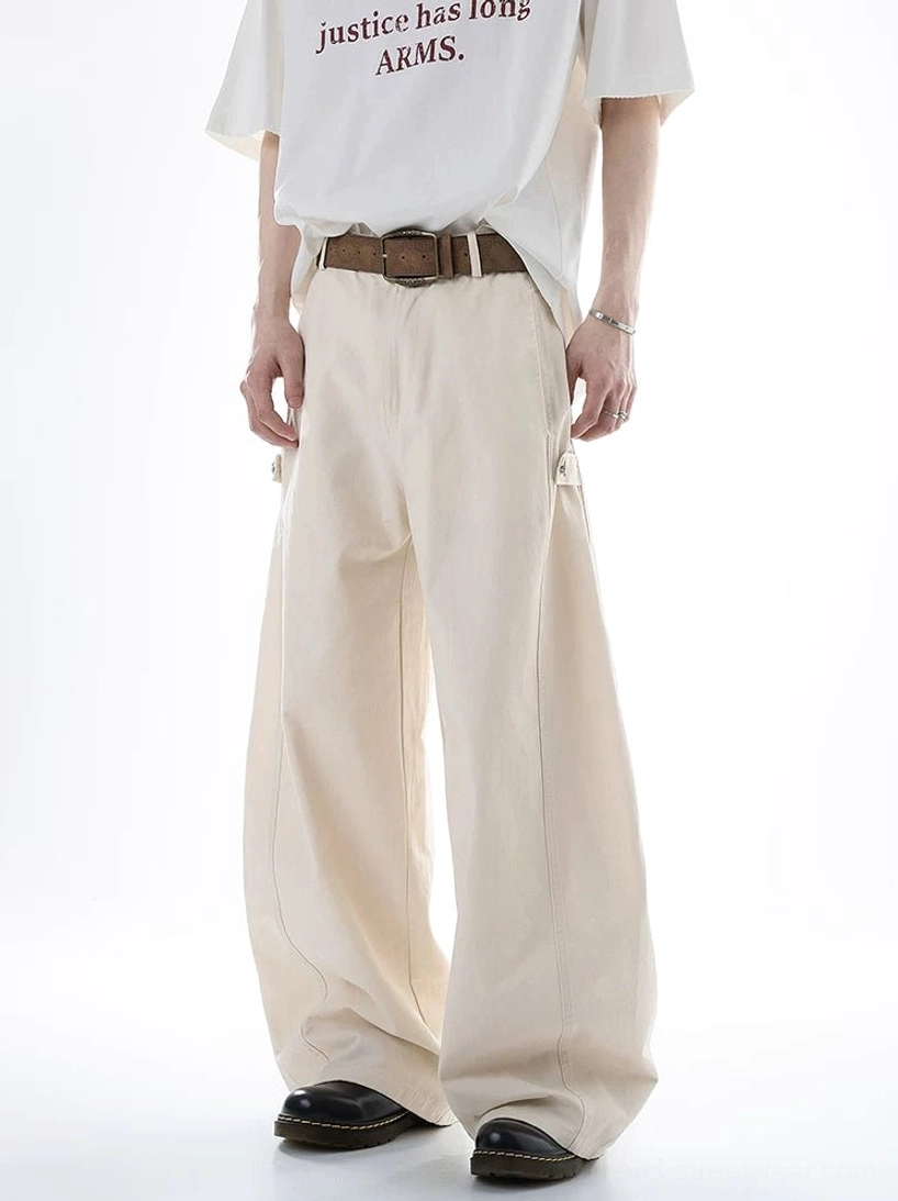 Beige Acubi ultra wide-leg cargo pants shown on a male model in a front full-body studio view with a high waist, brown leather belt styling, draped wide legs, and side cargo pocket