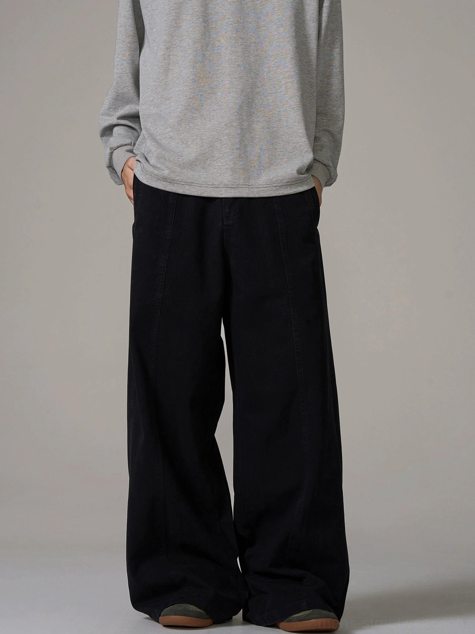 Front full-body male model wearing black wide-leg cotton trousers with relaxed Korean streetwear fit and hands in pockets