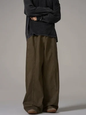 Back view of male model wearing brown wide-leg cotton trousers with central back waist seam and loose streetwear silhouette in studio