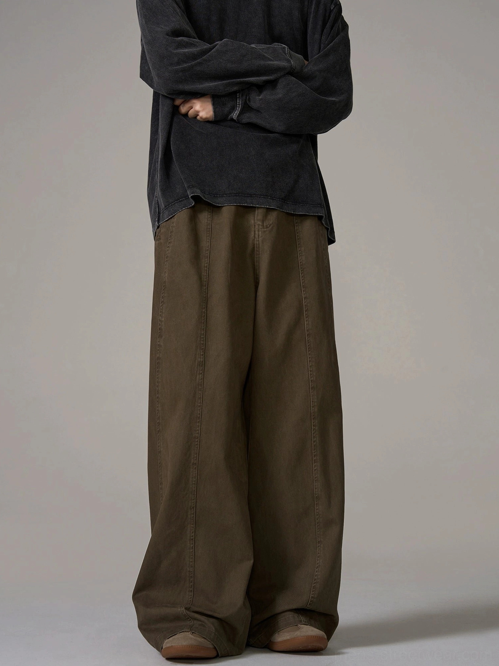 Back view of male model wearing brown wide-leg cotton trousers with central back waist seam and loose streetwear silhouette in studio