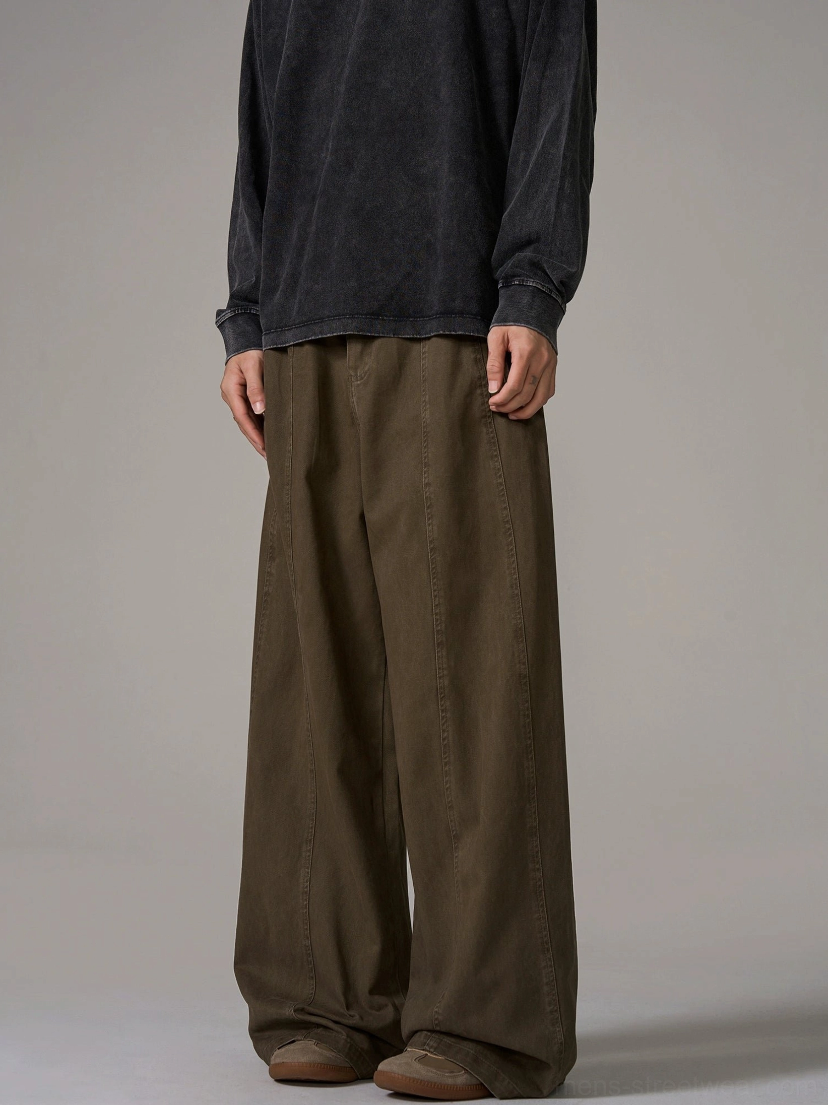 Front full-body male model wearing brown wide-leg cotton trousers with central front seam and relaxed Korean streetwear fit on grey studio background