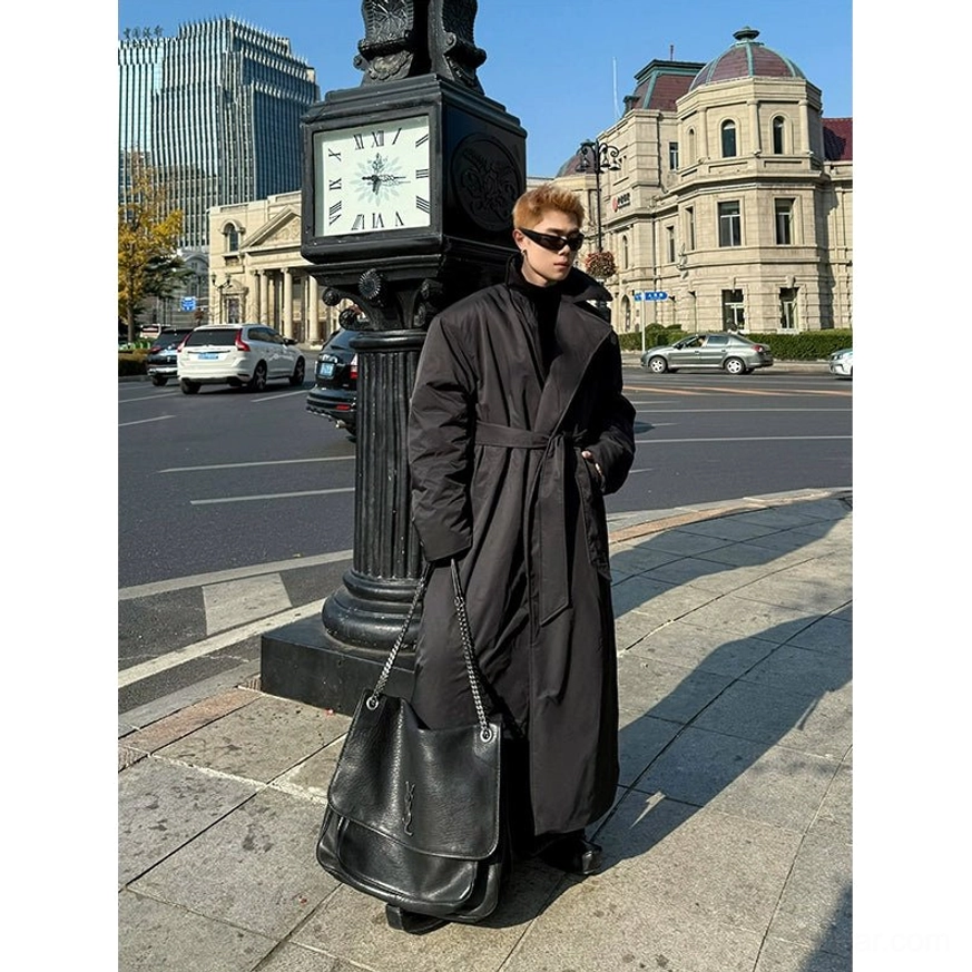 Front side view of an adjustable black waist belted padded overcoat with high stand collar ankle length design and Korean streetwear styling