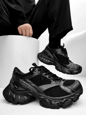 All-black chunky dad sneakers with mixed mesh and synthetic panels, decorative stitching, padded collar, and deep traction outsole