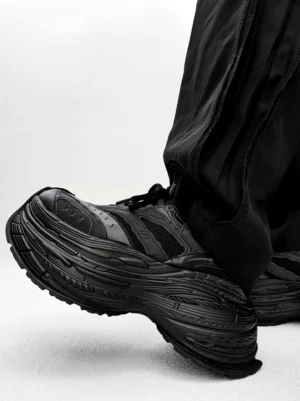 All black chunky platform sneakers with textured stacked sole and distressed mesh synthetic leather upper for streetwear outfits