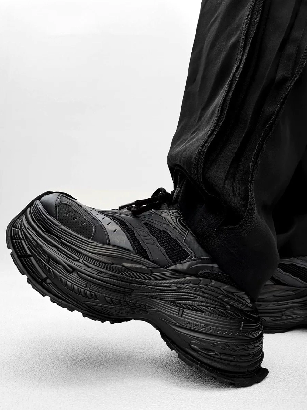 All black chunky platform sneakers with textured stacked sole and distressed mesh synthetic leather upper for streetwear outfits