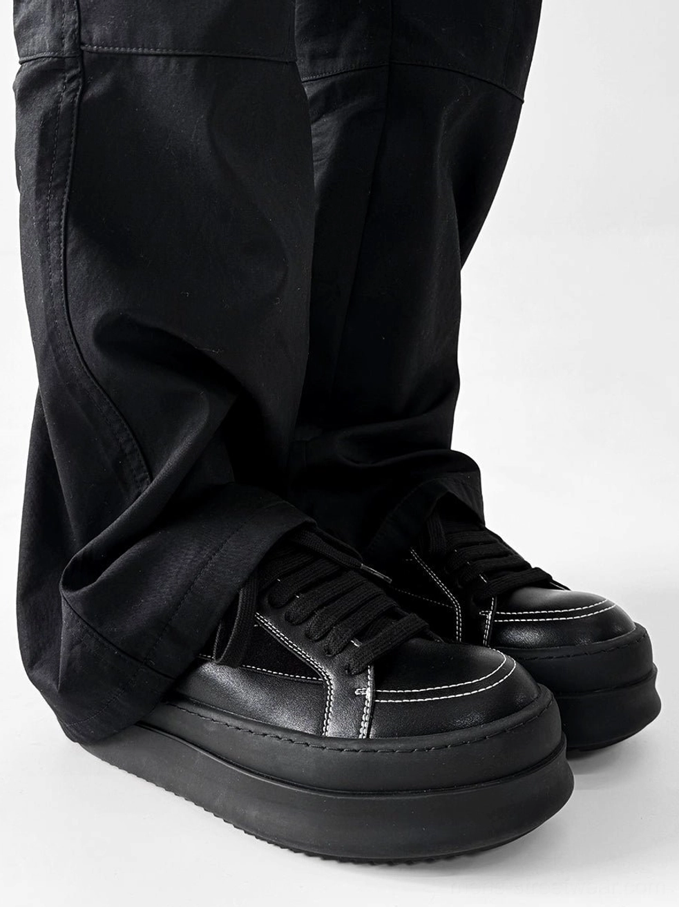 All-black chunky platform streetwear sneakers with matte elevated soles shown from the rear