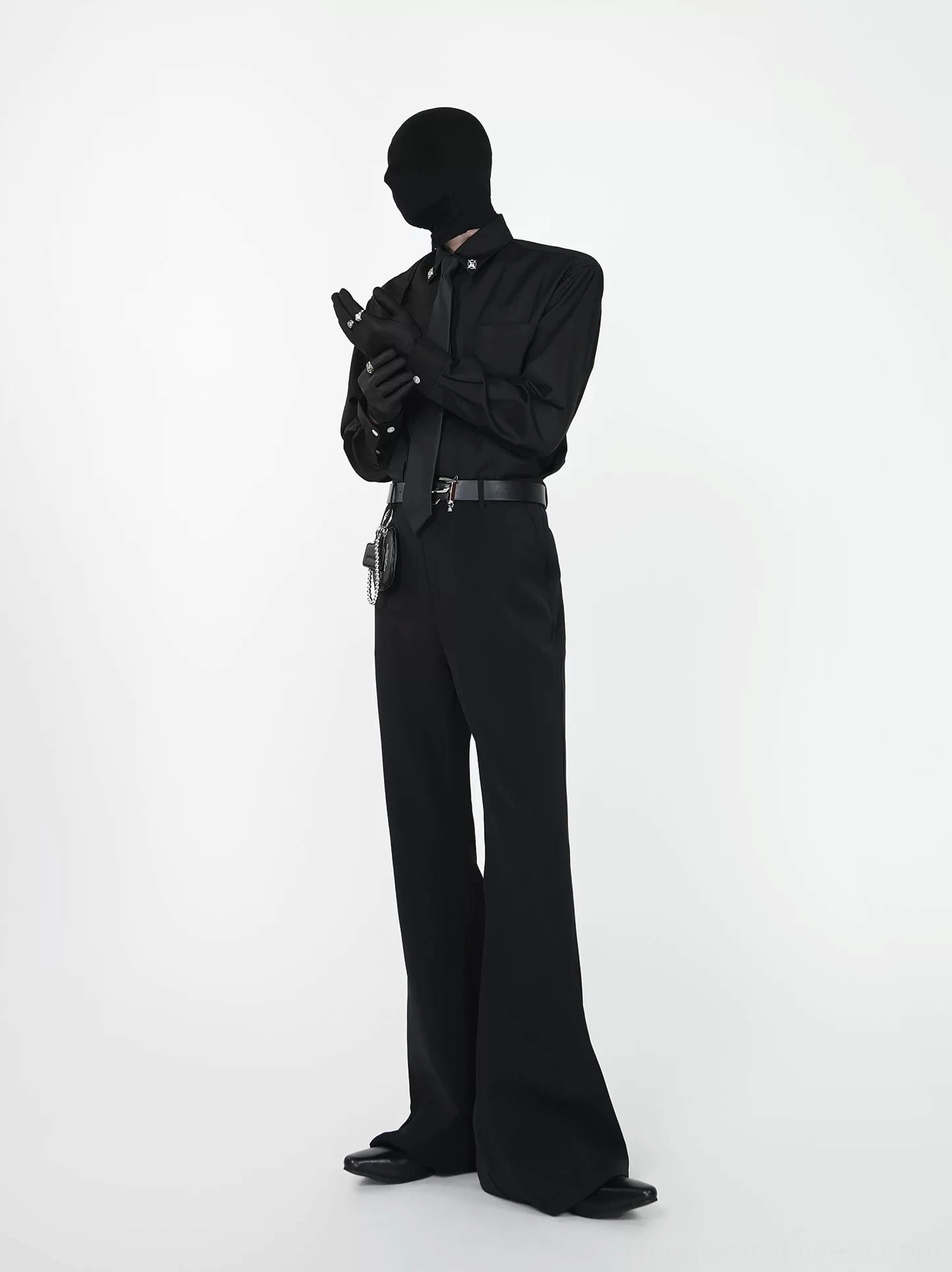 All-black long sleeve dress shirt and tonal tie set styled with black wide-leg trousers, belt, and chain accessory bag