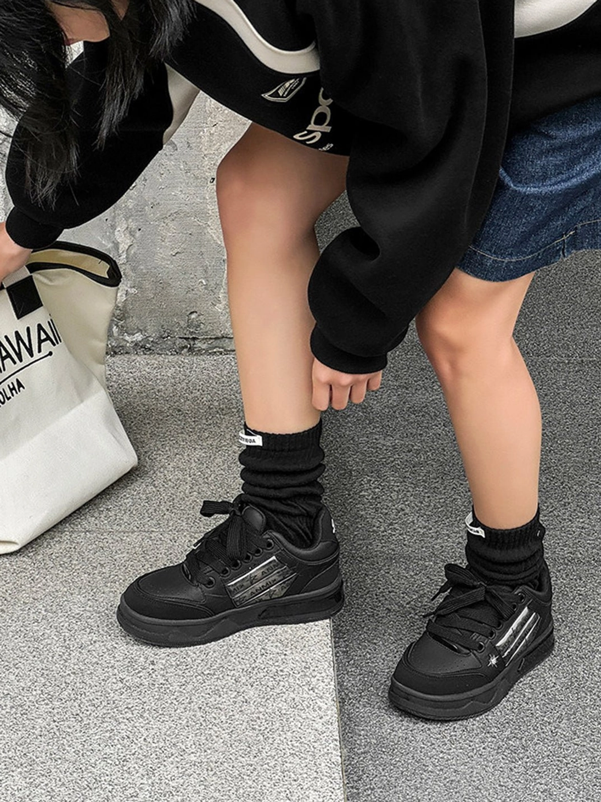 All black gothic skate sneakers with silver decorative side panels and thick platform soles worn with denim shorts and an oversized sweatshirt