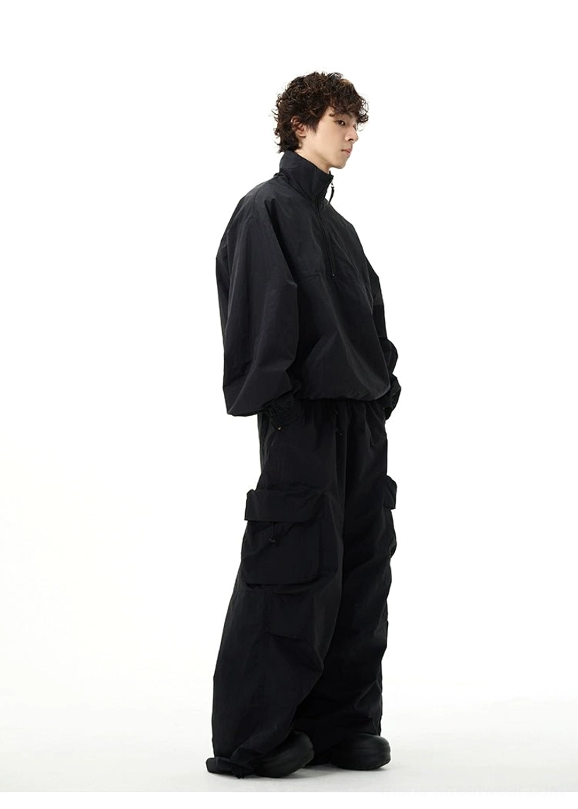 Full-body right side view of an all-black oversized windbreaker and baggy wide-leg cargo pants outfit