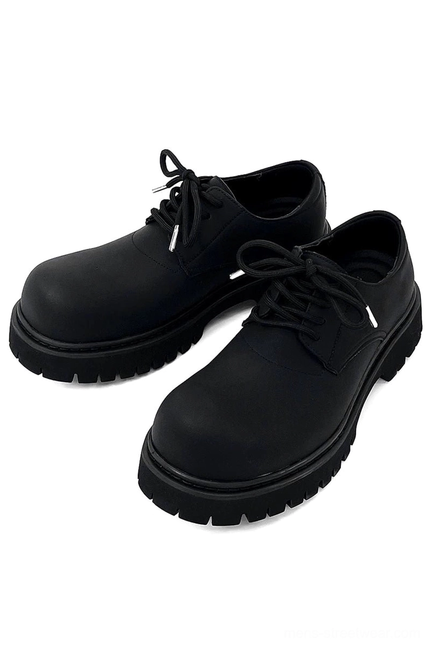 All-black platform derby footwear with substantial streetwear silhouette and textured outsole design