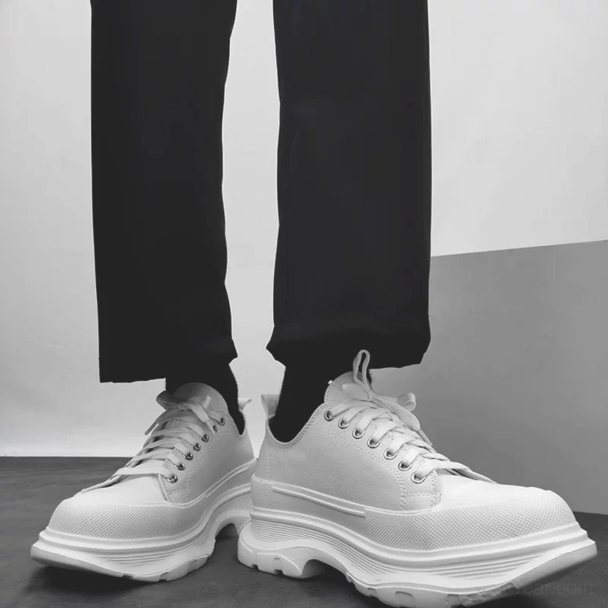 All-white chunky platform canvas sneakers worn with black formal trousers showing the thick rugged rubber sole
