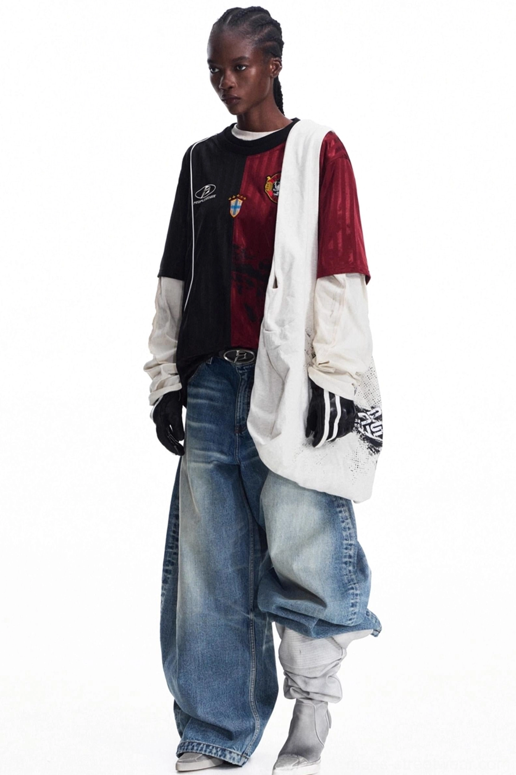 Androgynous streetwear styling with an oversized distressed canvas tote bag, retro football jersey, and baggy blue jeans