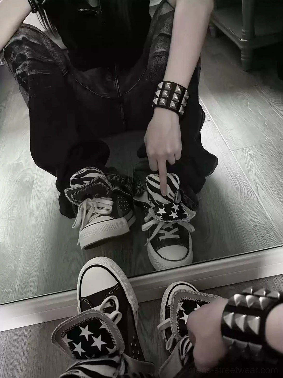 On-foot styling of animal-print and star high-top canvas sneakers with dark cargo pants and punk stud bracelet in an indoor streetwear look