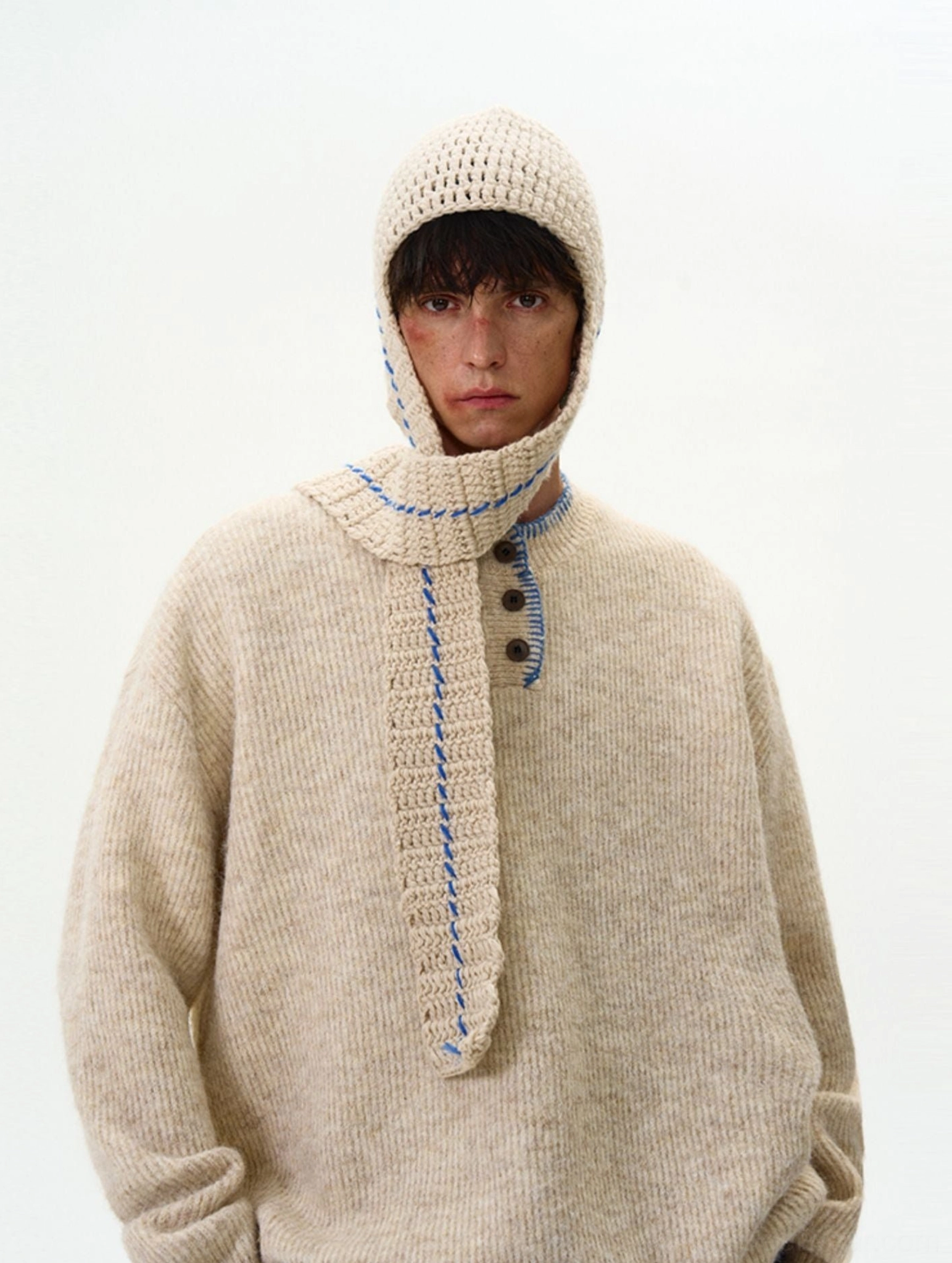 Close-up of apricot oversized knit sweater texture with contrast stitched Henley button placket and loose Korean fashion fit