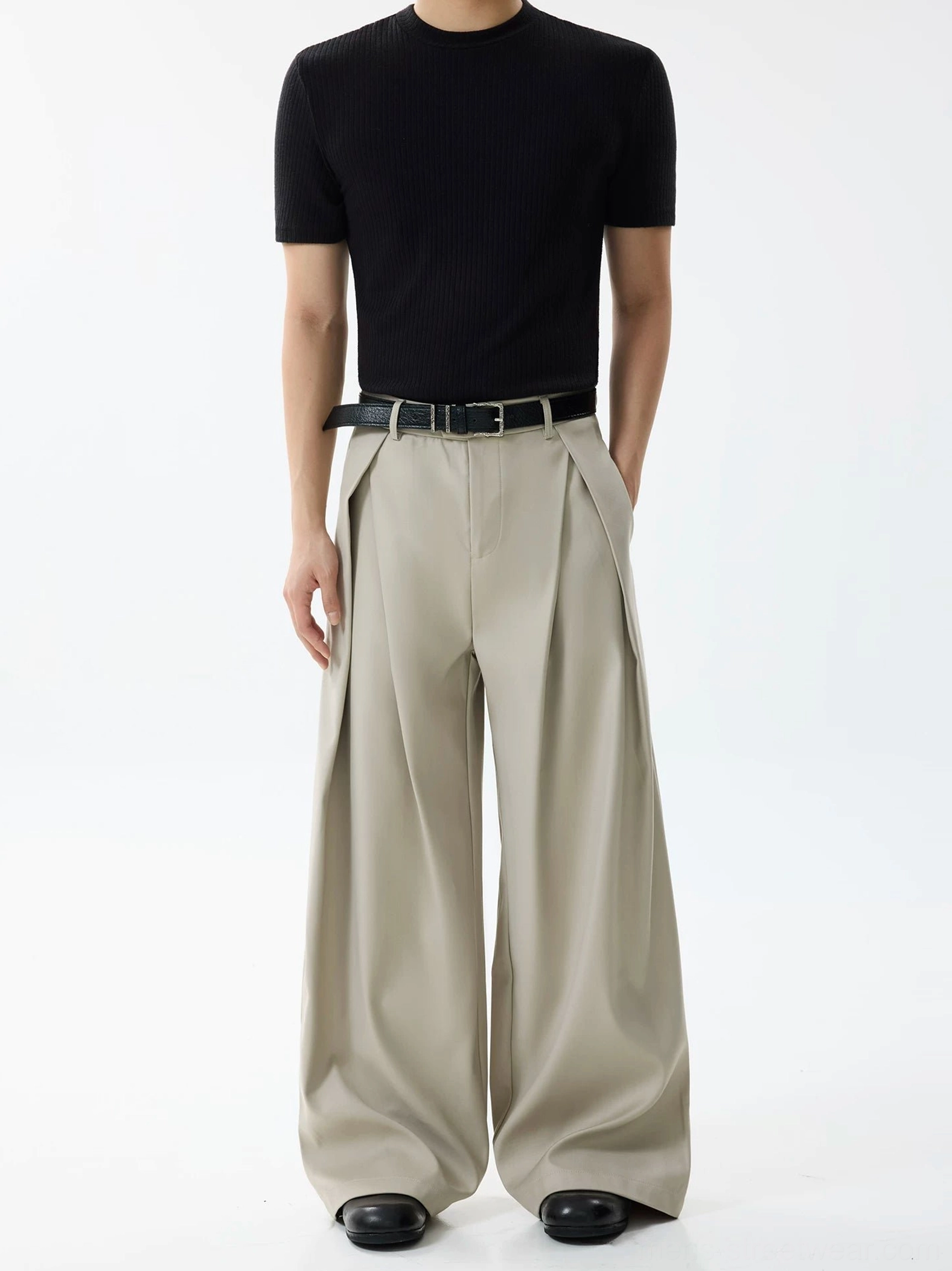 Light khaki apricot high-waisted pleated wide-leg trousers styled on a male model with black fitted tee and leather shoes