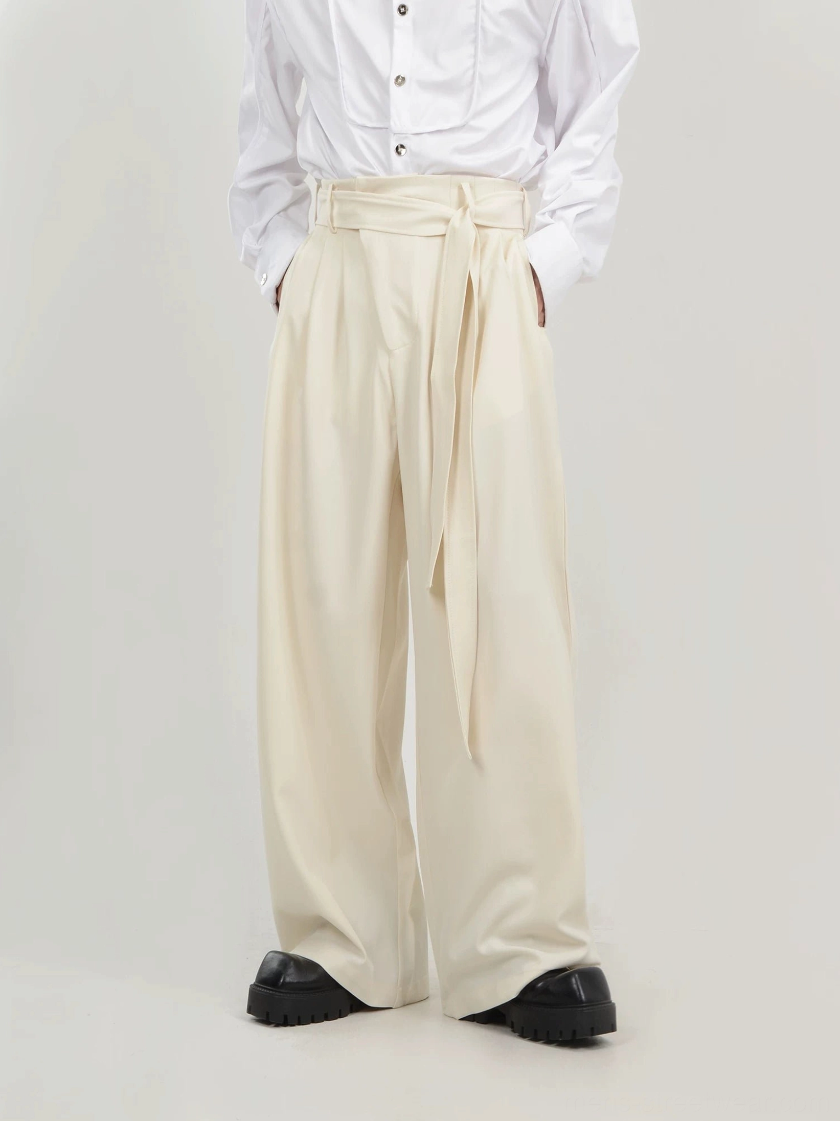 Apricot mens pleated wide-leg trousers with integrated sash belt front view and hands in side pockets
