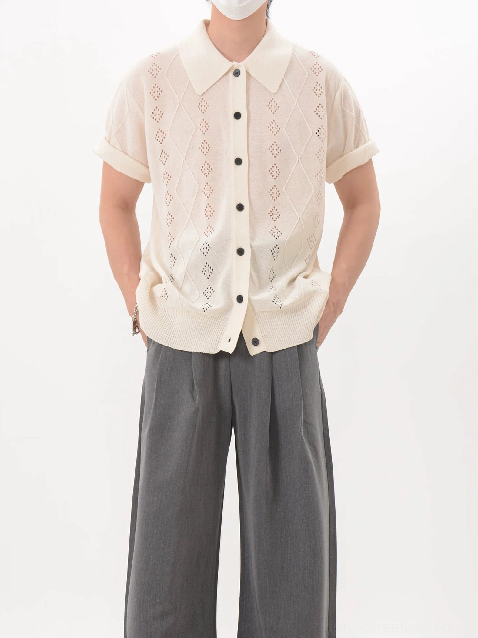 Apricot openwork argyle knit polo cardigan styled with gray wide-leg trousers in a front three-quarter view