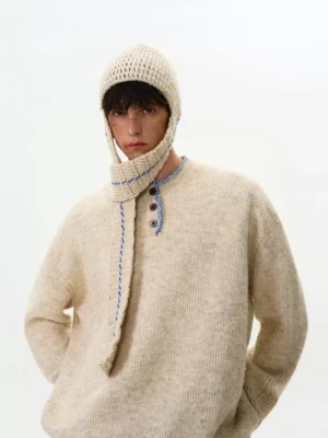 Three-quarter view of an apricot oversized Henley knit sweater with contrast stitching, button placket, and relaxed Seoul streetwear styling