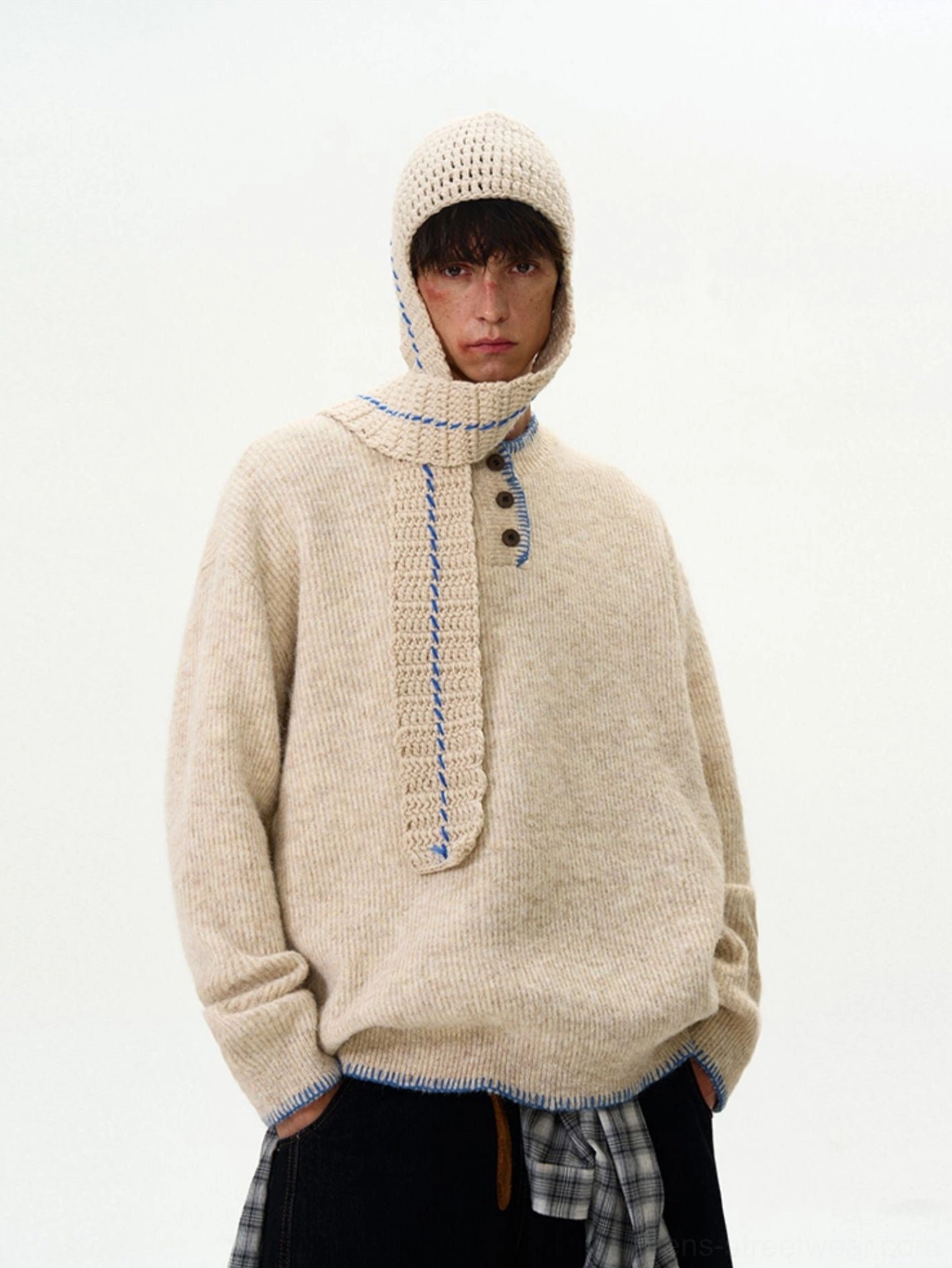 Full-body front view of an apricot oversized contrast-stitch knit sweater styled with a plaid shirt layer for East Asian streetwear