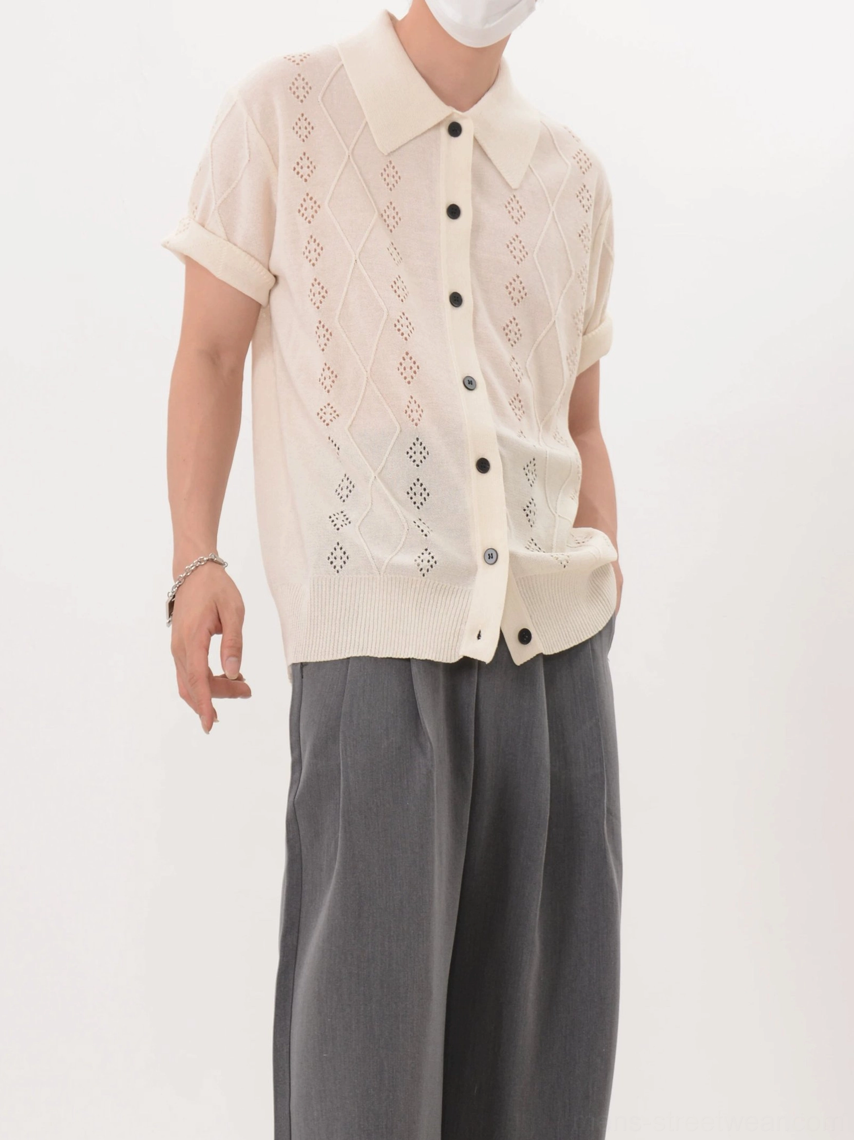 Apricot short-sleeve argyle hollow knit polo cardigan worn with gray trousers in a relaxed front view