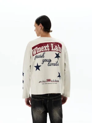 Full back view of apricot vintage graphic long sleeve tee featuring distressed retro typography, star sleeve prints, and relaxed streetwear styling