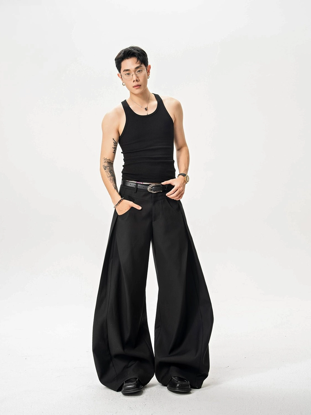 Black ultra wide-leg twill trousers worn by male model with black tank top in white studio front full-body view