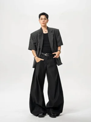 Black tailored ultra wide-leg trousers styled with striped short-sleeve blazer, tank top, belt, and leather shoes