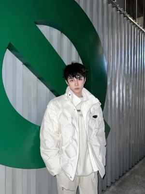 White diamond quilted puffer jacket shown from the front three quarter view on a male model in a modern industrial outdoor setting