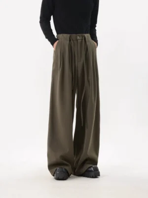 Army green Acubi pleated drawstring wide-leg trousers styled with a black fitted top and chunky platform shoes in a full-body studio view