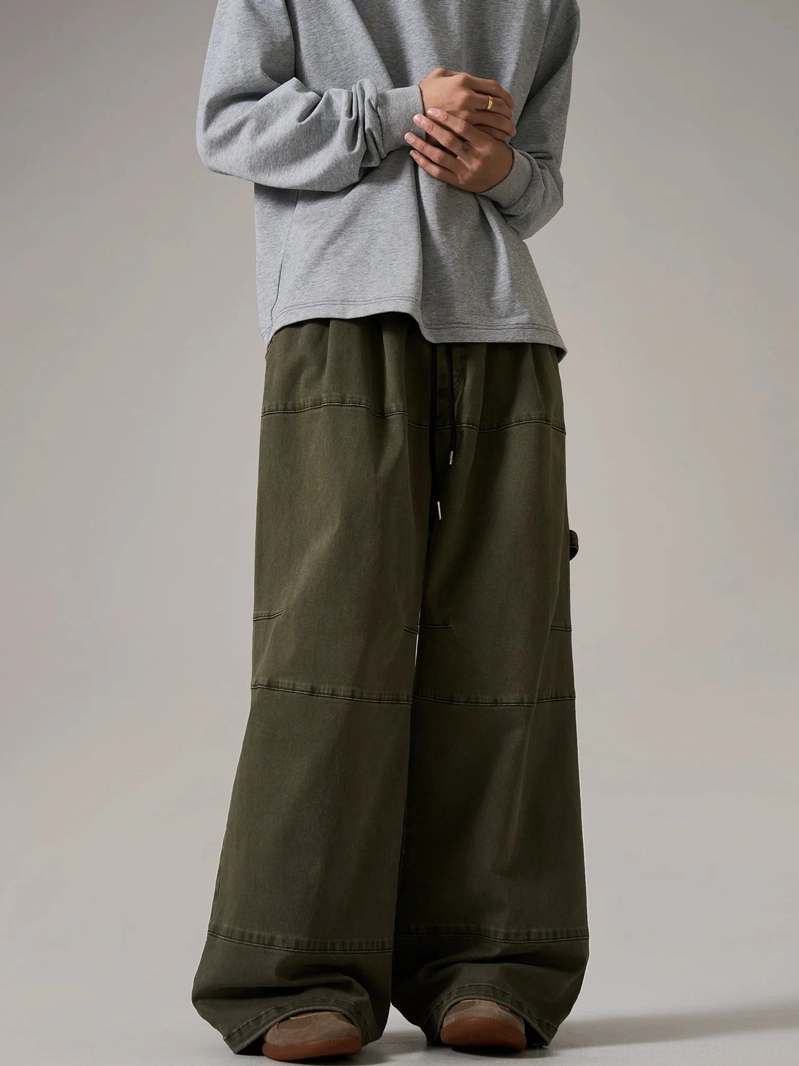 Army green oversized cargo pants with wide skater silhouette, paneled contrast stitching, adjustable drawstring waist, and contemporary gorpcore styling