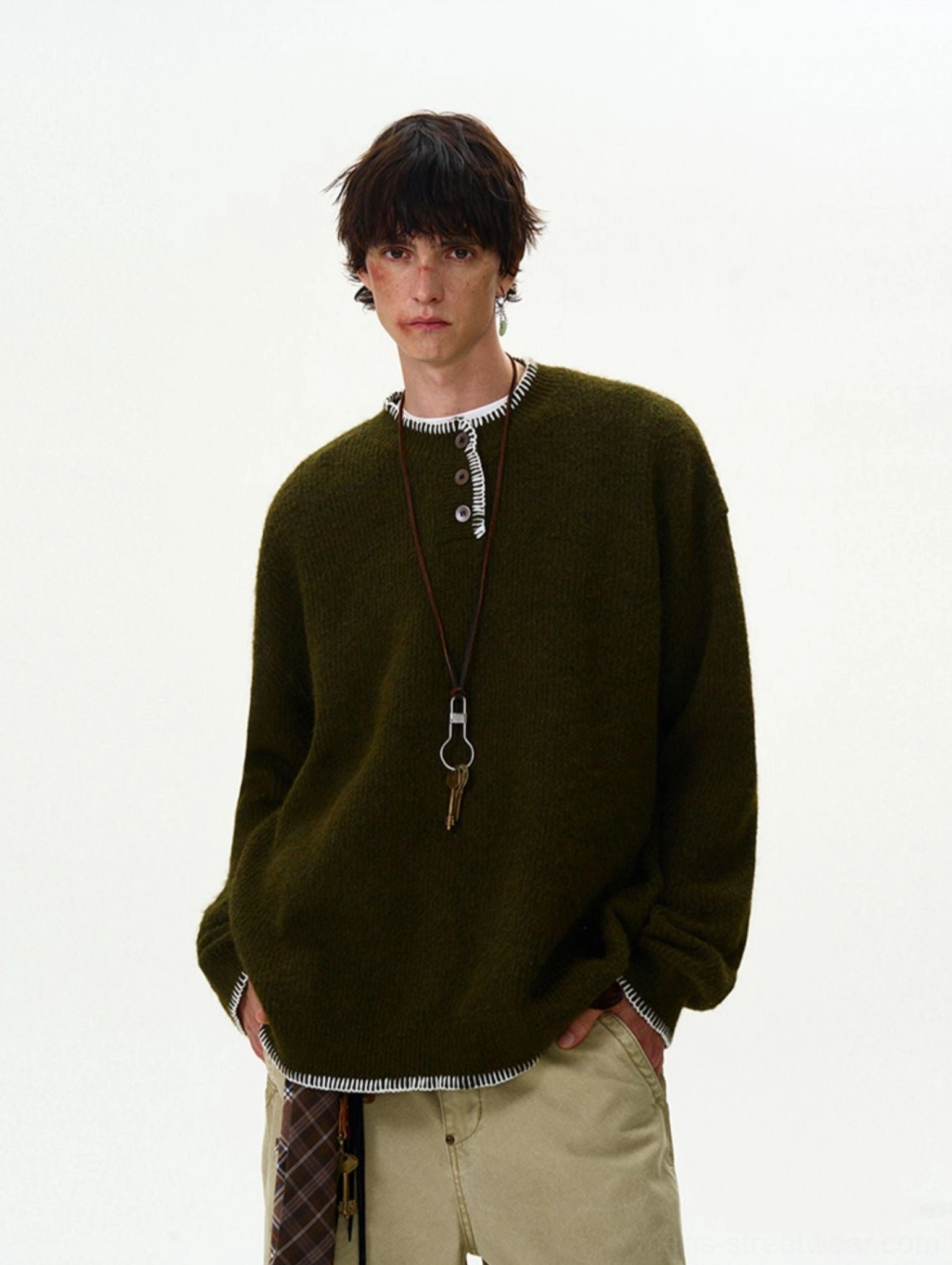 Army green oversized contrast-stitch Henley knit sweater styled with khaki trousers and a utility keychain crossbody accessory