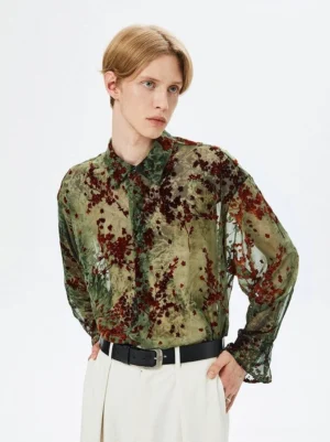 Male model wearing an army green semi-sheer floral button-up shirt with dark red botanical print in a front three-quarter studio view