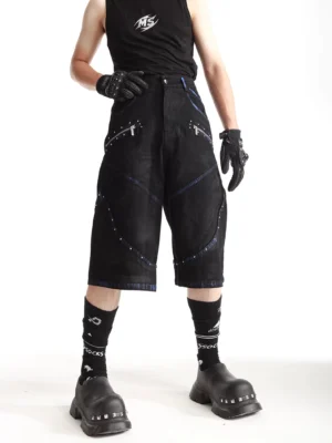 Three-quarter front view of ash blue wide-leg denim shorts with silver studs curved contrast stitching and zipper pockets