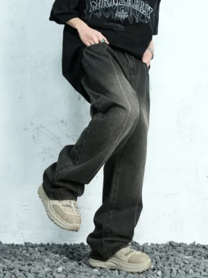 Side three-quarter view of relaxed ash fade wide leg jeans showing the loose silhouette, faded denim wash, waistband, pockets, and stacked streetwear fit