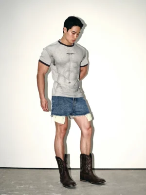 Ash gray contrast ringer tee styled with frayed denim shorts and brown cowboy boots in a full body side profile streetwear outfit