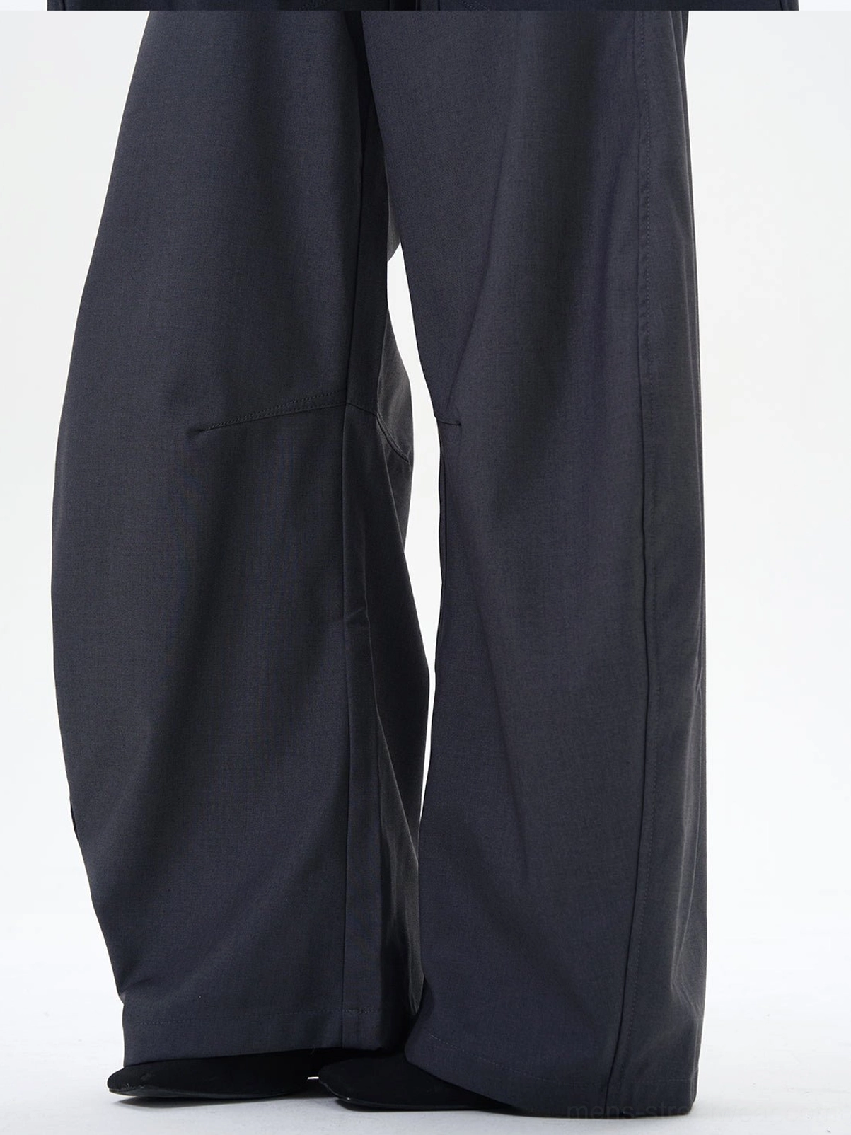 Low-angle close-up of dark ash wide-leg palazzo pants showing curved side seams and dramatic fabric drape