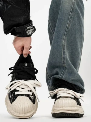 Two-tone distressed chunky shell-toe sneakers with black and off-white color blocking, frayed textile upper, dual laces, and oversized streetwear sole